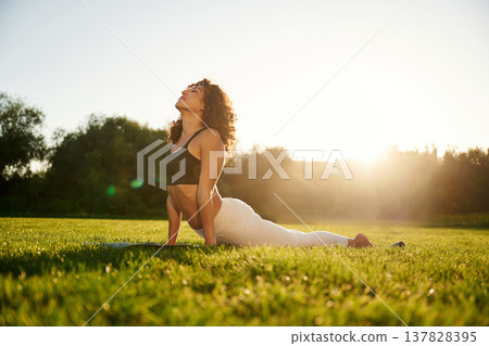 Against sunlight beam. Young fitness woman is on the field outdoors Against sunlight beam. Young fitness woman is on the field outdoors 137828395