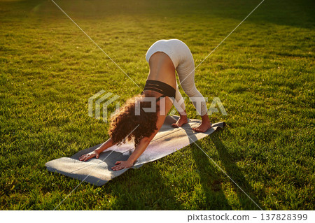 Doing yoga on a mat. Sportive woman doing fitness on the field 137828399