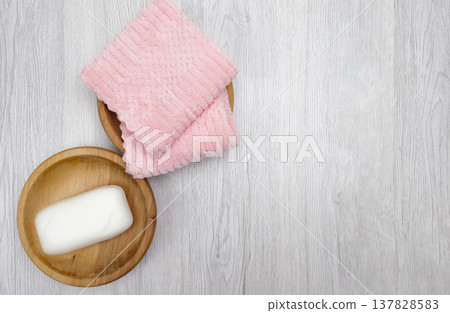 A white table holding rolls of clean pink towels, a houseplant, shampoo, conditioner, and soap, perfect for promotional messages. top view 137828583