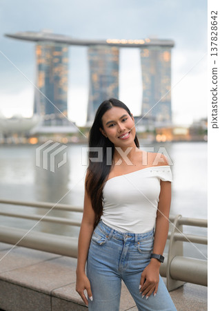 Asian tourist woman posing by the waterfront at Marina Bay Singapore during evening Asian tourist woman posing by the waterfront at Marina Bay Singapore during evening 137828642