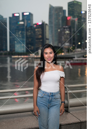 Asian tourist woman posing by the waterfront at Marina Bay Singapore during evening Asian tourist woman posing by the waterfront at Marina Bay Singapore during evening 137828648