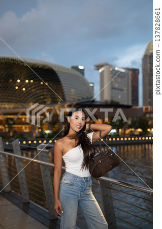 Asian tourist woman posing by the waterfront at Marina Bay Singapore during evening Asian tourist woman posing by the waterfront at Marina Bay Singapore during evening 137828661