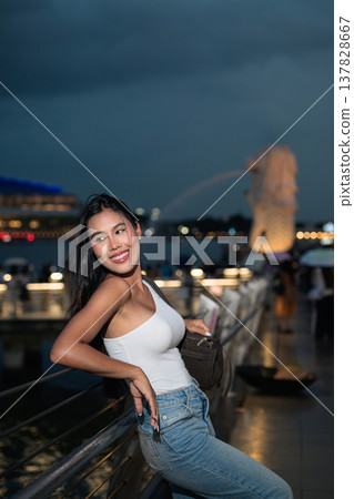 Asian tourist woman posing by the waterfront at Marina Bay Singapore during evening Asian tourist woman posing by the waterfront at Marina Bay Singapore during evening 137828667