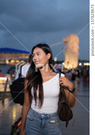 Asian tourist woman posing by the waterfront at Marina Bay Singapore during evening Asian tourist woman posing by the waterfront at Marina Bay Singapore during evening 137828673