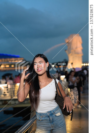 Asian tourist woman posing by the waterfront at Marina Bay Singapore during evening Asian tourist woman posing by the waterfront at Marina Bay Singapore during evening 137828675