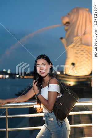 Asian tourist woman posing by the waterfront at Marina Bay Singapore during evening Asian tourist woman posing by the waterfront at Marina Bay Singapore during evening 137828677