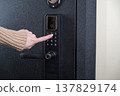 A woman opens a modern smart door lock with a digital keypad using a code. 137829174