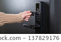 A woman opens a modern smart door lock using a contactless key. 137829176