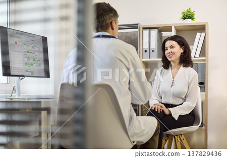 Doctor and patient discussing diagnosis in consultation in modern clinic office 137829436