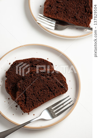 Slices of rich double chocolate pound cake on white plates. Top view Slices of rich double chocolate pound cake on white plates. Top view 137829504