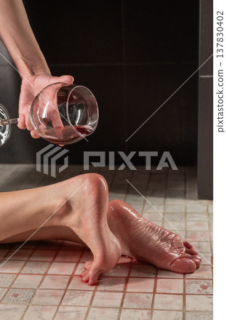 Foot fetish. A woman pours wine from a glass onto her feet in the shower. 137830402