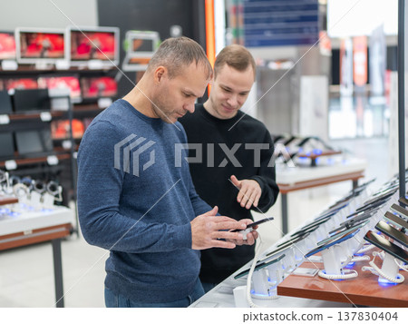 Two Caucasian men are choosing a smartphone in a store. Two Caucasian men are choosing a smartphone in a store. 137830404