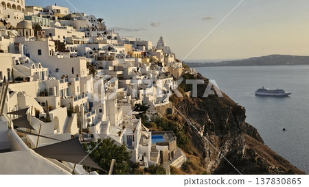 Sunset view over Santorini whitewashed cliffside overlooking the caldera with cruise ships below. 137830865