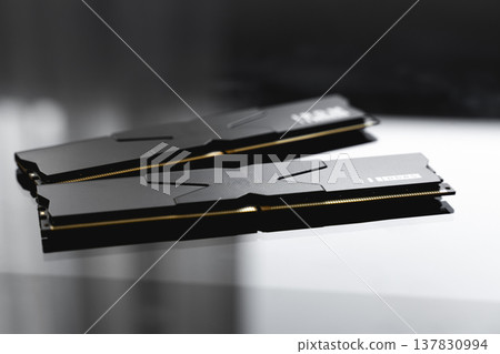 Black DDR5 RAM memory modules placed on a dark, glossy surface. RAM shortages on the market, rising prices, and increased demand driven by the growing need for AI training. 137830994