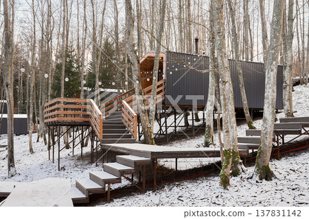 Enchanting small lodge enveloped in snow with welcoming porch light 137831142