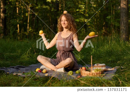 Tranquil scene of woman relaxing with apples in forest at sunset 137831171