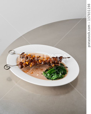 Artistic presentation of roasted skewer with crunchy nuts and tender greens Artistic presentation of roasted skewer with crunchy nuts and tender greens 137831198