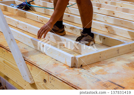Man works on wooden structure during construction process in residential area Man works on wooden structure during construction process in residential area 137831419