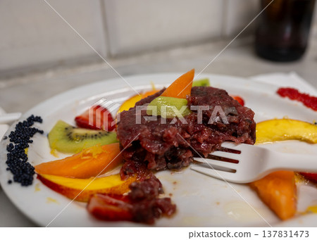 Red tuna tartare plate served with various slices of fresh fruit including kiwi, strawberry, and peach, garnished with black caviar, offering a gourmet appetizer experience Red tuna tartare plate served with various slices of fresh fruit including kiwi, strawberry, and peach, garnished with black caviar, offering a gourmet appetizer experience 137831473