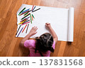 Young female child drawing with pencils on large white paper on wooden floor 137831568
