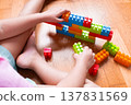 Young child building colorful plastic blocks on wood floor 137831569