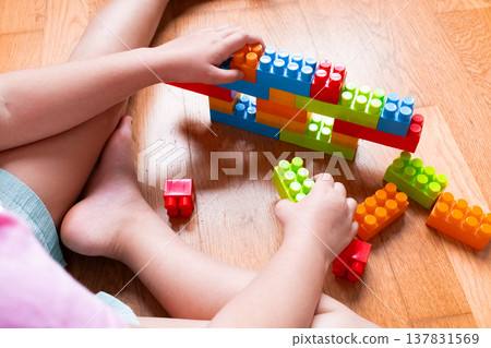 Young child building colorful plastic blocks on wood floor Young child building colorful plastic blocks on wood floor 137831569