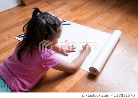 Young asian girl drawing on white paper with pencils on wooden floor Young asian girl drawing on white paper with pencils on wooden floor 137831570