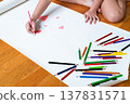 Child drawing with colored pencils on large white paper 137831571