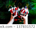 Child holding colorful wooden nutcracker ornaments against Christmas tree 137831572