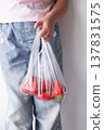 Child holding bag of fresh strawberries in clear plastic bag 137831575
