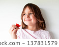 Caucasian female child smiling with strawberry against white background 137831579