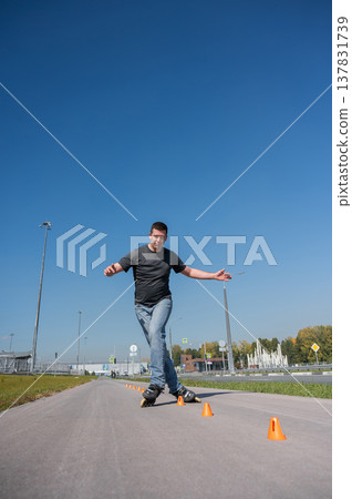 A Caucasian man rollerblades around the slalom course. 137831739