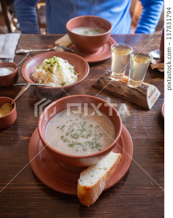 [Ukraine] White soup in ceramic bowls and vodka line a wooden table in a restaurant in Lviv, western Ukraine. 137831794