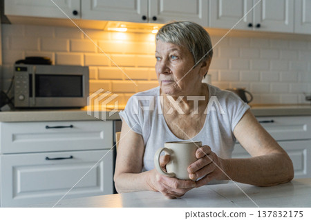 Senior woman drinking coffee contemplating in kitchen Senior woman drinking coffee contemplating in kitchen 137832175