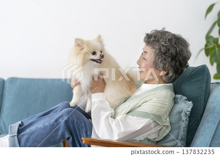 A senior woman smiling and relaxing with her dog. A senior woman smiling and relaxing with her dog. 137832235
