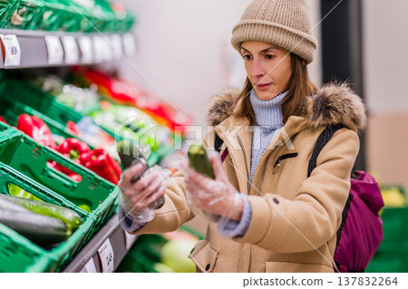 Woman experiencing food problems in supermarket carefully selecting vegetables Woman experiencing food problems in supermarket carefully selecting vegetables 137832264