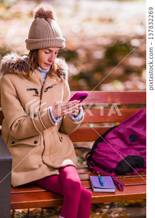 Woman with anorexia using smartphone in park having personal time Woman with anorexia using smartphone in park having personal time 137832269