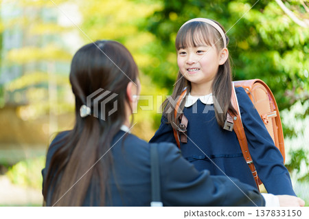 A girl and a mum carrying a school bag A girl and a mum carrying a school bag 137833150