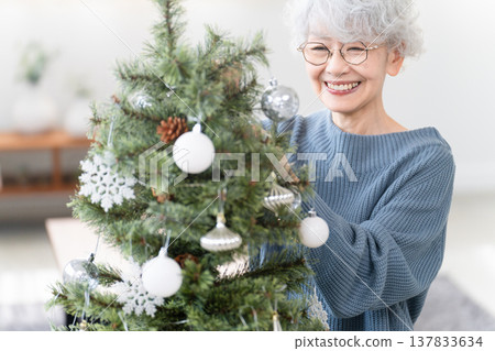 Senior woman decorating Christmas tree with ornaments 137833634