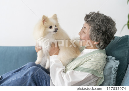 A senior woman smiling and relaxing with her dog. A senior woman smiling and relaxing with her dog. 137833974