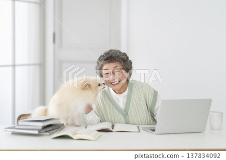 A senior woman who works at a desk and her beloved dog A senior woman who works at a desk and her beloved dog 137834092