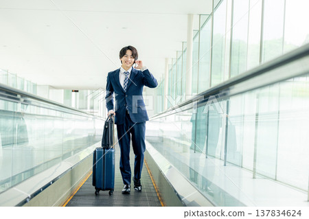 一名男子在機場拖著行李箱 137834624