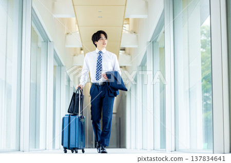 A young man carrying a carry-on bag A young man carrying a carry-on bag 137834641