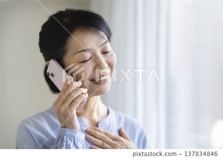 一位年近六十的女士正在用智慧型手機通話 一位年近六十的女士正在用智慧型手機通話 137834846