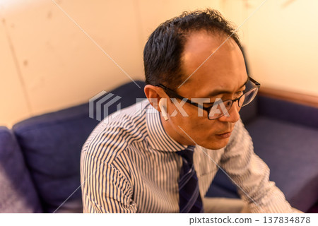 一位中年男子戴著耳機打電話。 137834878