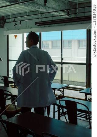 一個身穿白大褂的男人凝視著窗外。 137834919