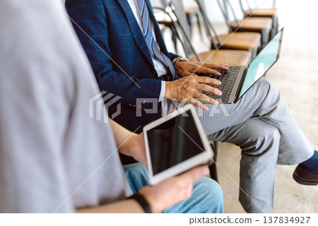 A professor working on a PC and a student with a tablet. 137834927
