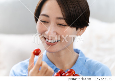 Young woman eating cherry tomatoes lifestyle image Young woman eating cherry tomatoes lifestyle image 137834970