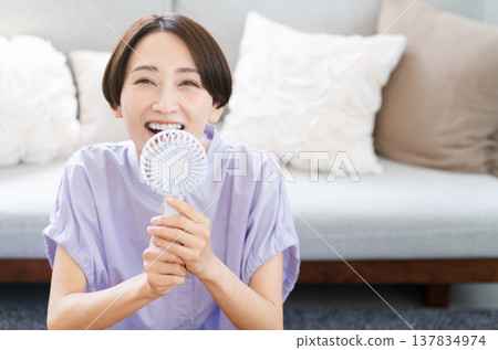 Young woman using a hand fan Lifestyle image Young woman using a hand fan Lifestyle image 137834974