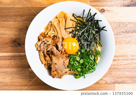 油拌麵配豬肉和生蛋；自製什錦麵，盛於木桌上。 137835100